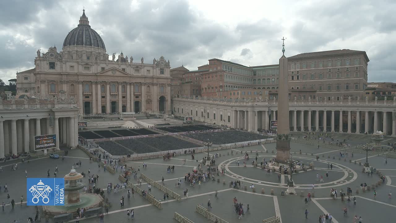 St. Peter's Basilica and St. Peter's Square in Vatican City are shown on an overcast day with many people sparsely scattered throughout the square.