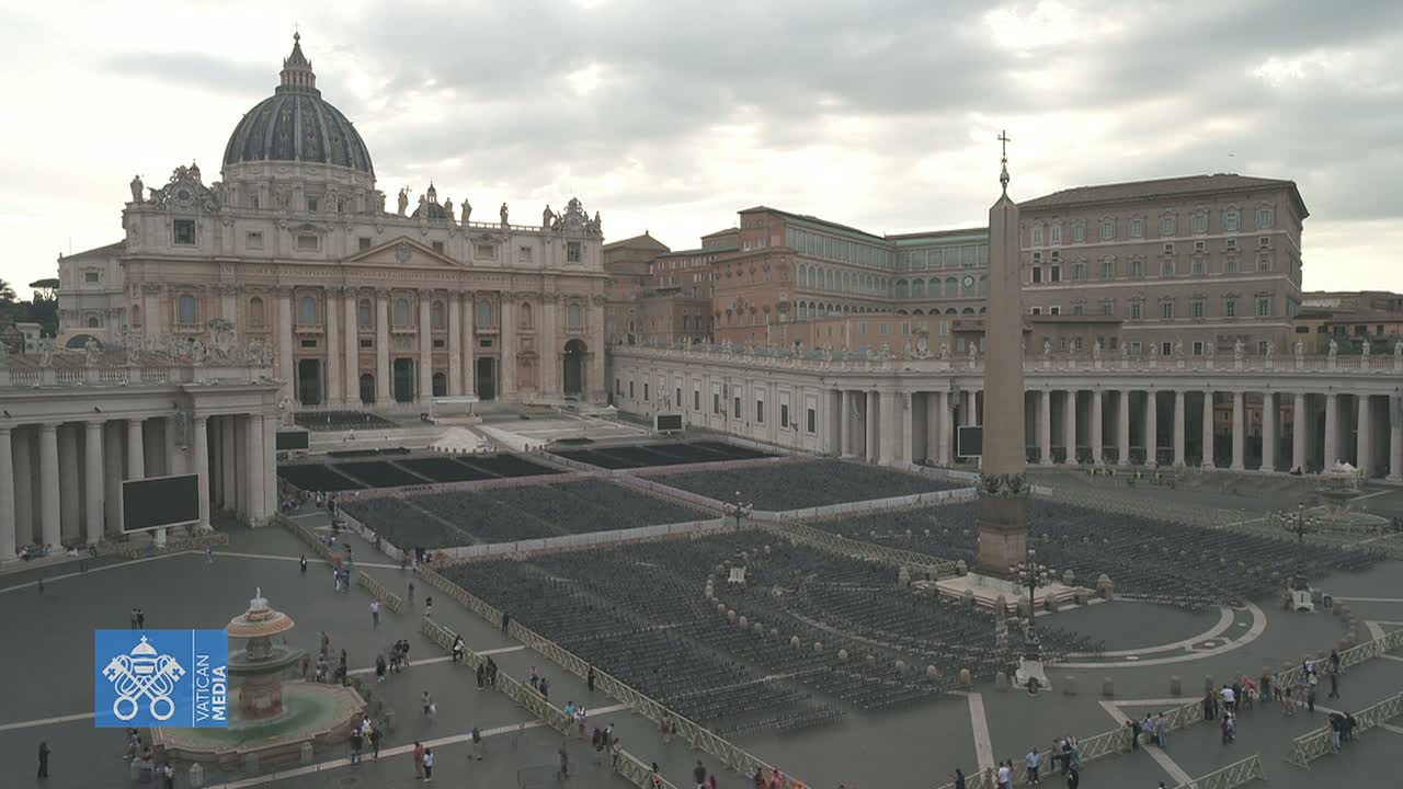 St. Peter's Basilica and Square in Vatican City are shown on an overcast day, with many chairs set up in the square.