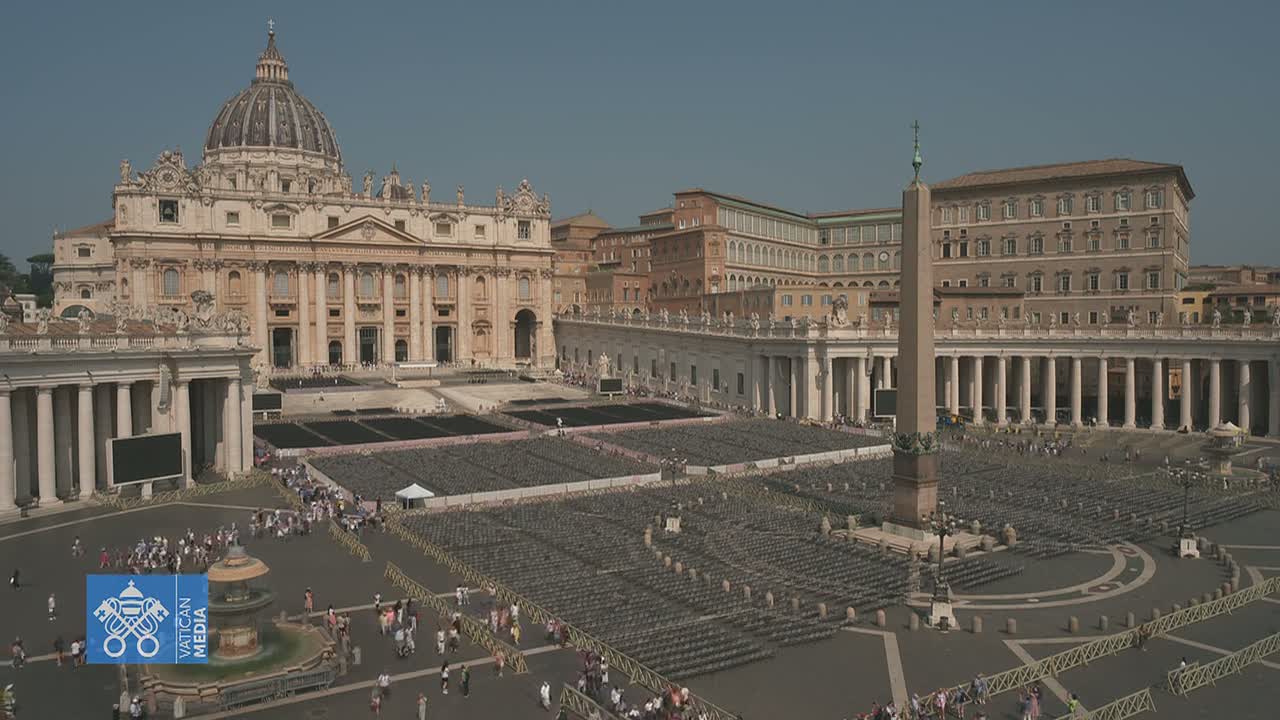 St. Peter's Square in Vatican City, under a clear sky, is filled with numerous rows of empty chairs, with a few people scattered throughout the vast plaza.