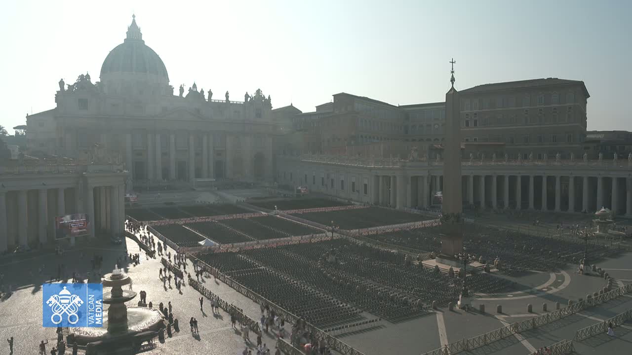 St. Peter's Basilica and St. Peter's Square in Vatican City are shown on a hazy, sunny day, with many chairs set up in the square.