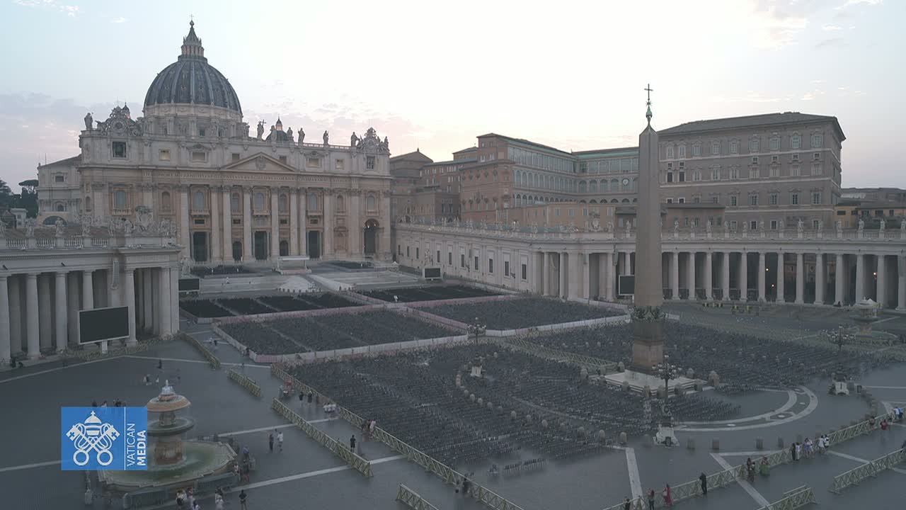 St. Peter's Basilica and St. Peter's Square in Vatican City are shown under a cloudy, dusky sky, with numerous chairs set up in the square.