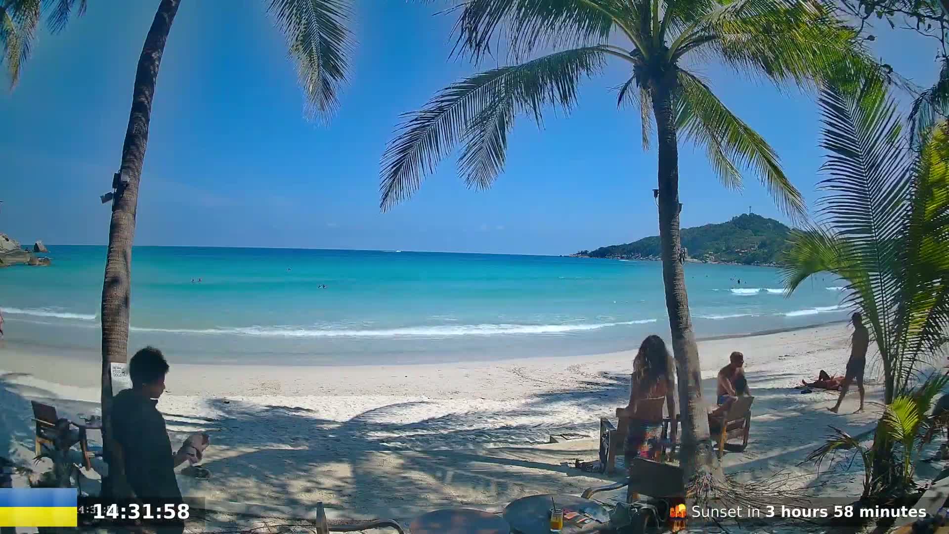A sunny beach scene with turquoise water, white sand, palm trees, and a few people relaxing.