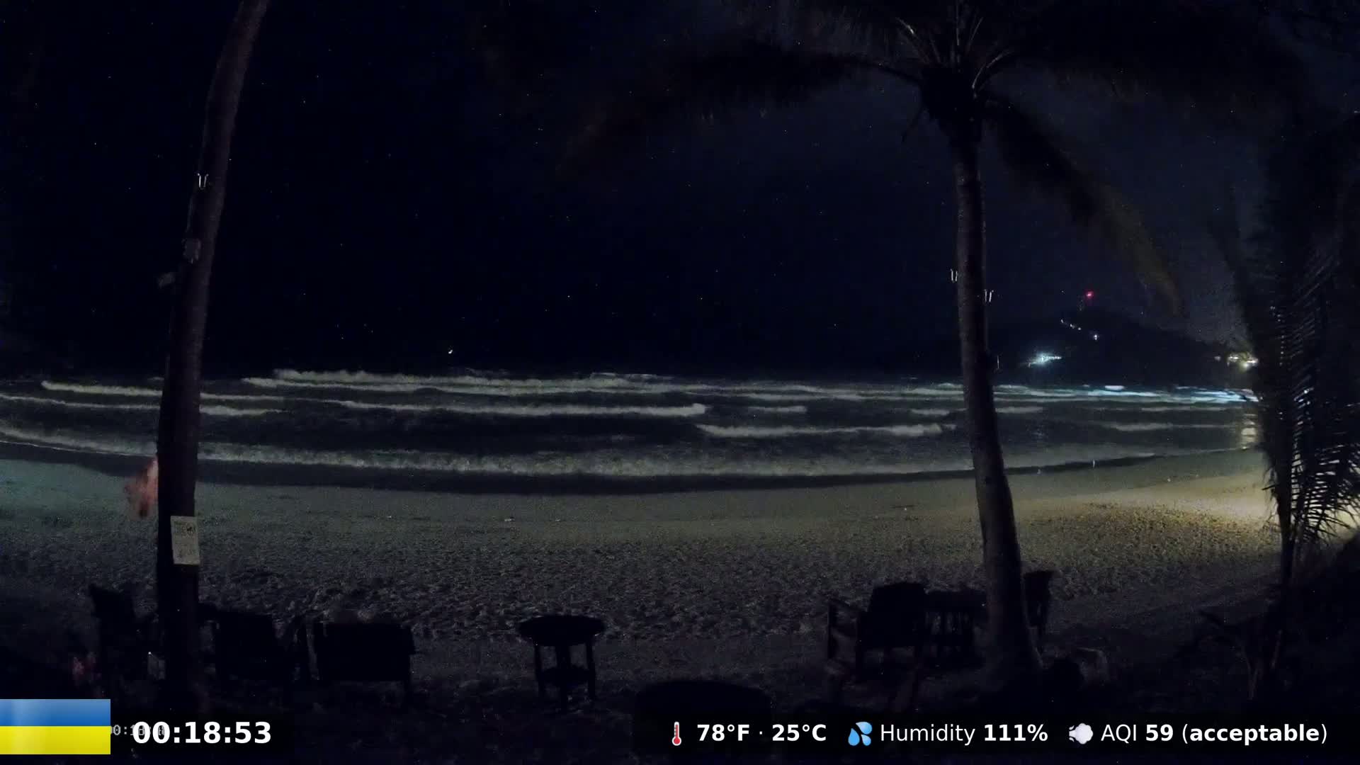A nighttime beach scene shows moderate waves lapping a sandy shore under a clear, starry sky.