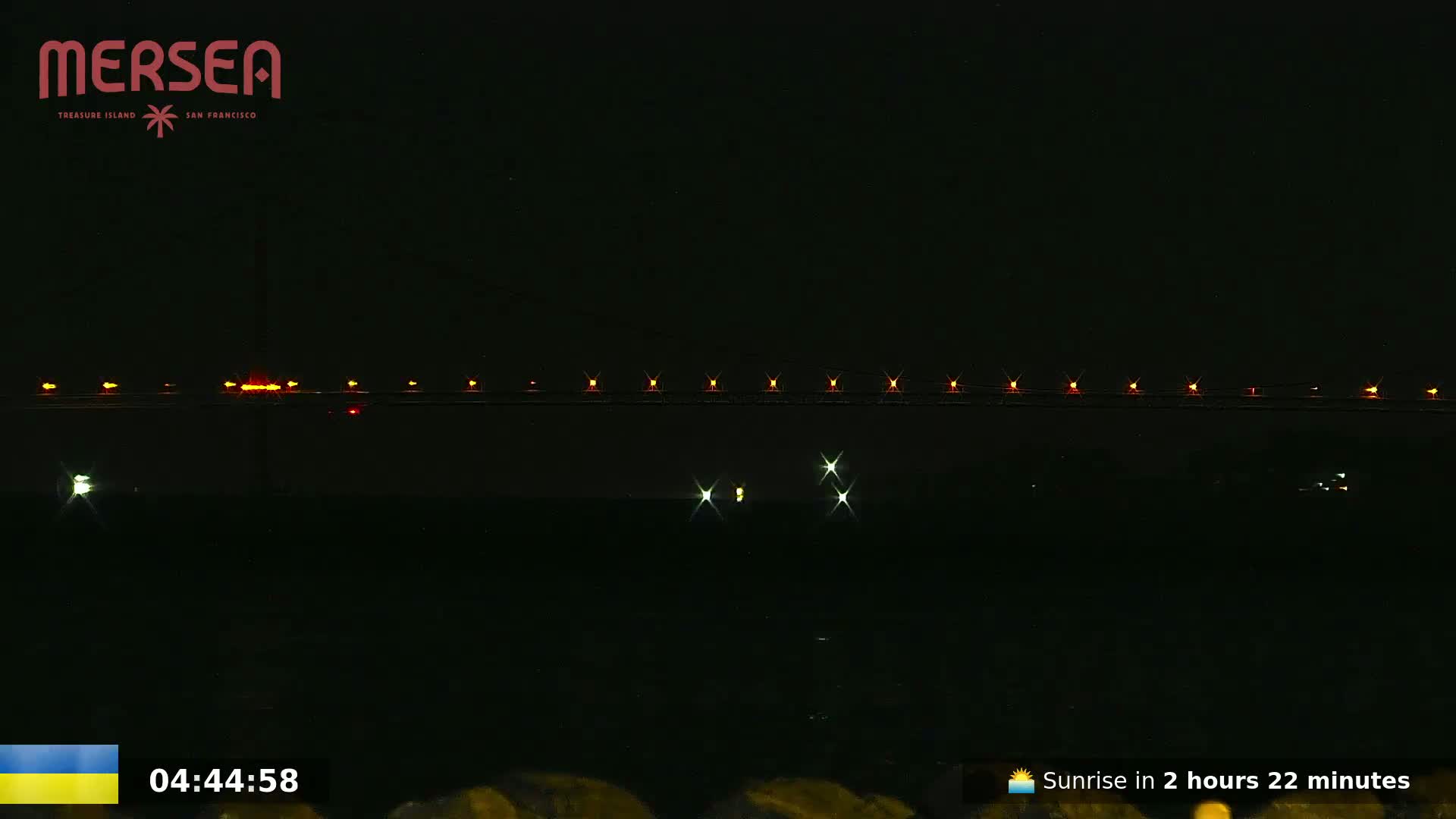 A long bridge with lights is visible at night.
