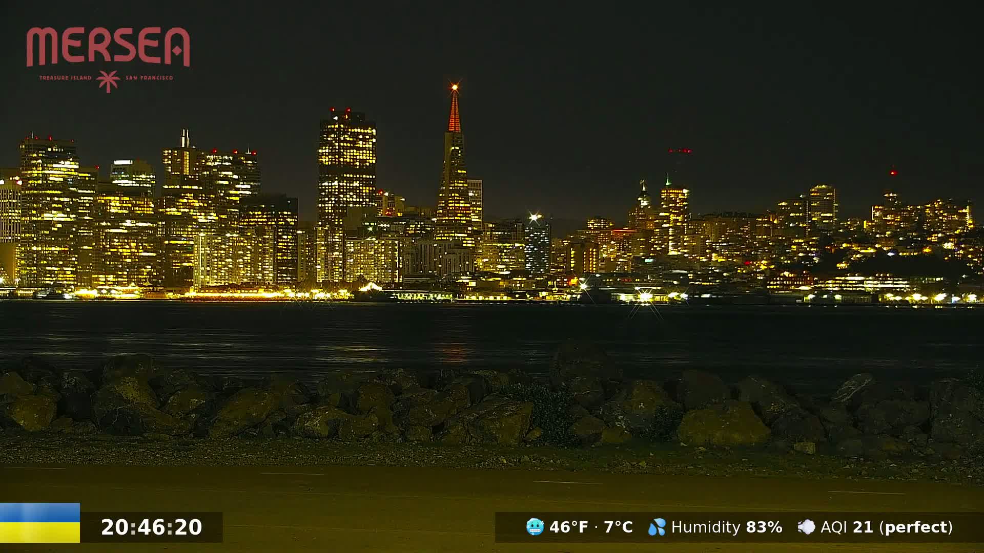 A brightly lit San Francisco city skyline is viewed from across a body of water at night, under a clear sky.
