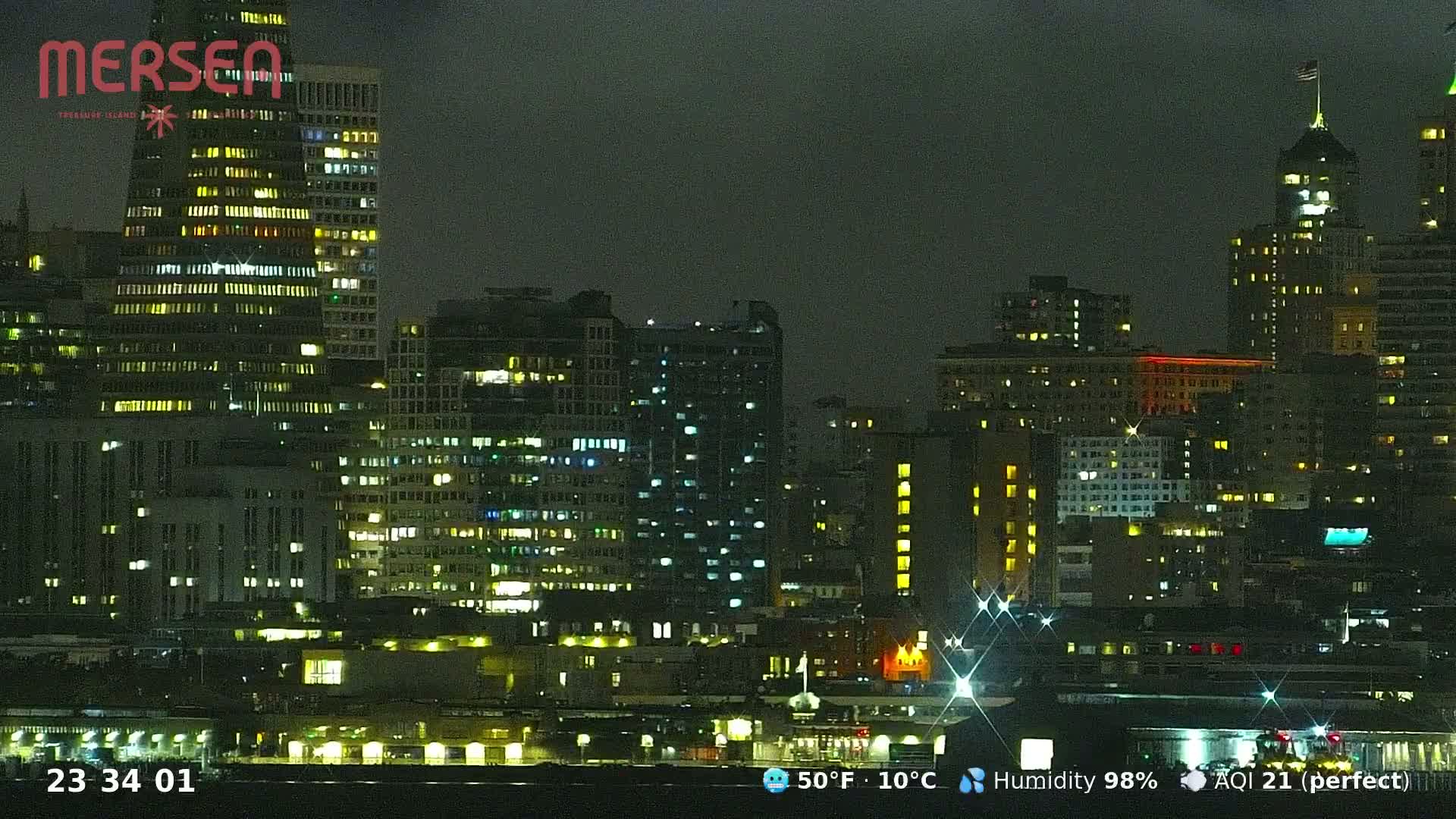 A nighttime cityscape with many illuminated buildings under a dark, overcast sky.