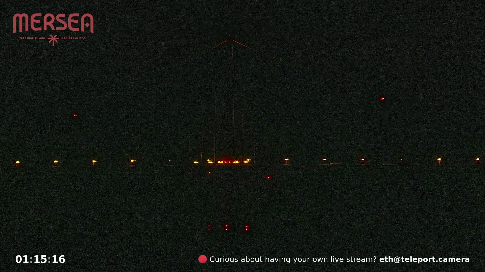 A tall structure with lights at its base is visible at night, illuminated by several small lights along a dark landscape.