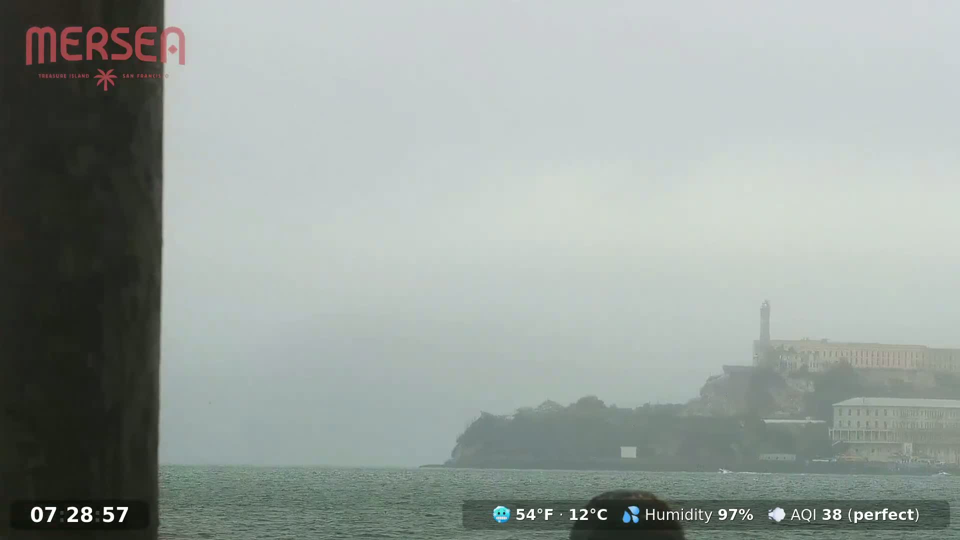 A hazy, foggy view shows Alcatraz Island across a body of water.