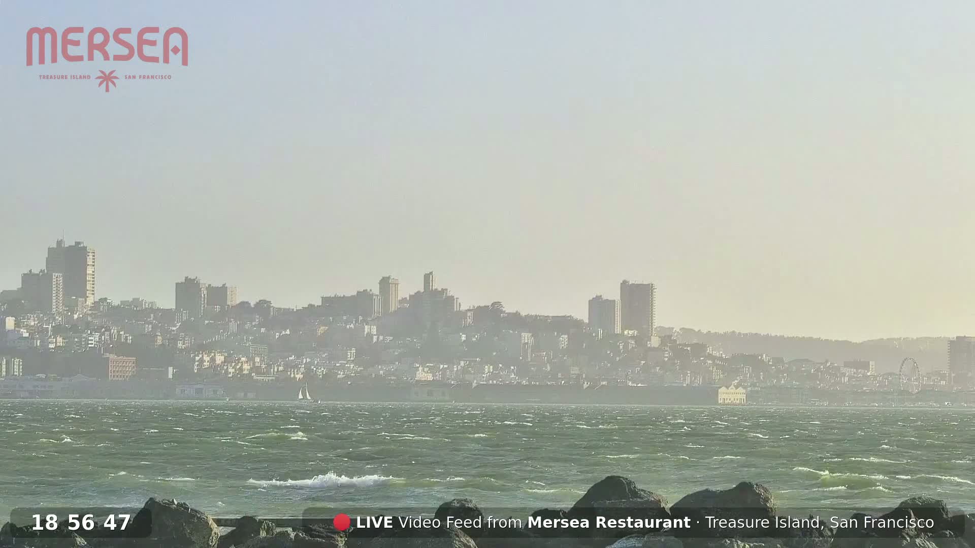 A hazy view of a city skyline across a choppy body of water.
