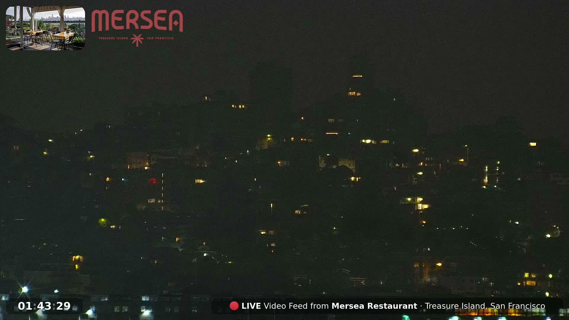 A dark cityscape is visible at night, illuminated by numerous scattered lights from buildings and streetlights under a clear sky.