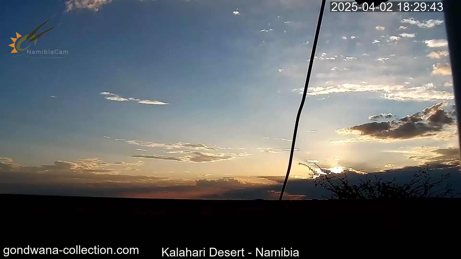 A partly cloudy sunset over a flat, dark landscape.