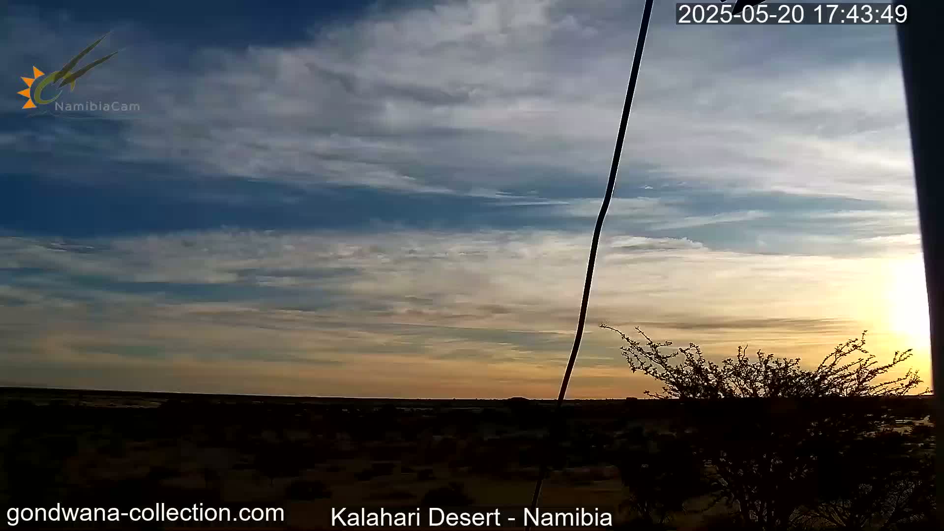 A desert landscape at sunset under a mostly clear sky with thin, wispy clouds.