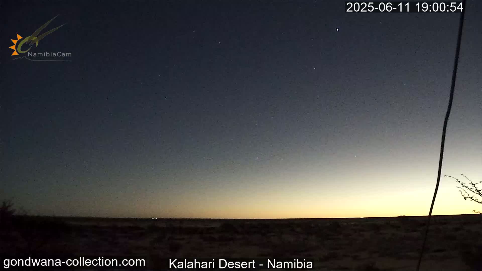 A dark desert landscape is shown at twilight under a mostly clear, starry sky.