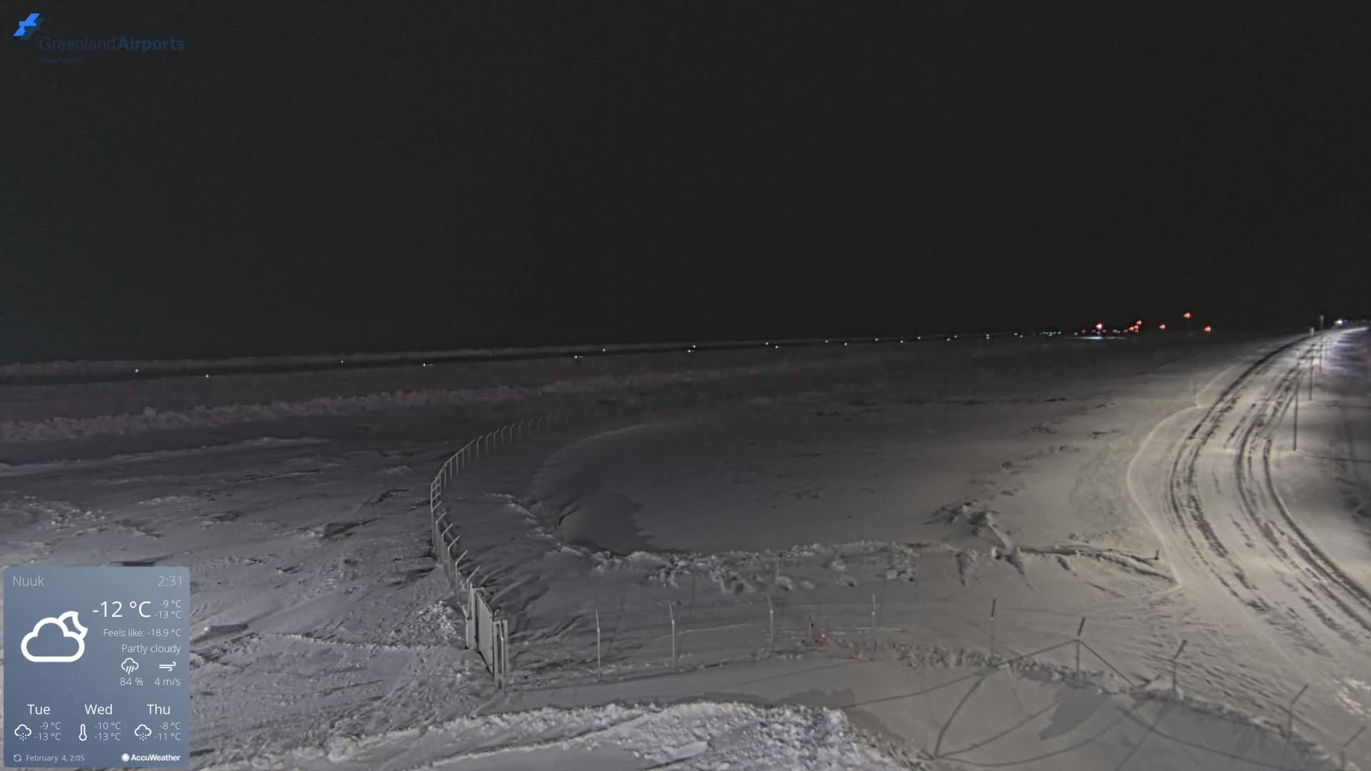 A snow-covered airfield at night under partly cloudy skies.