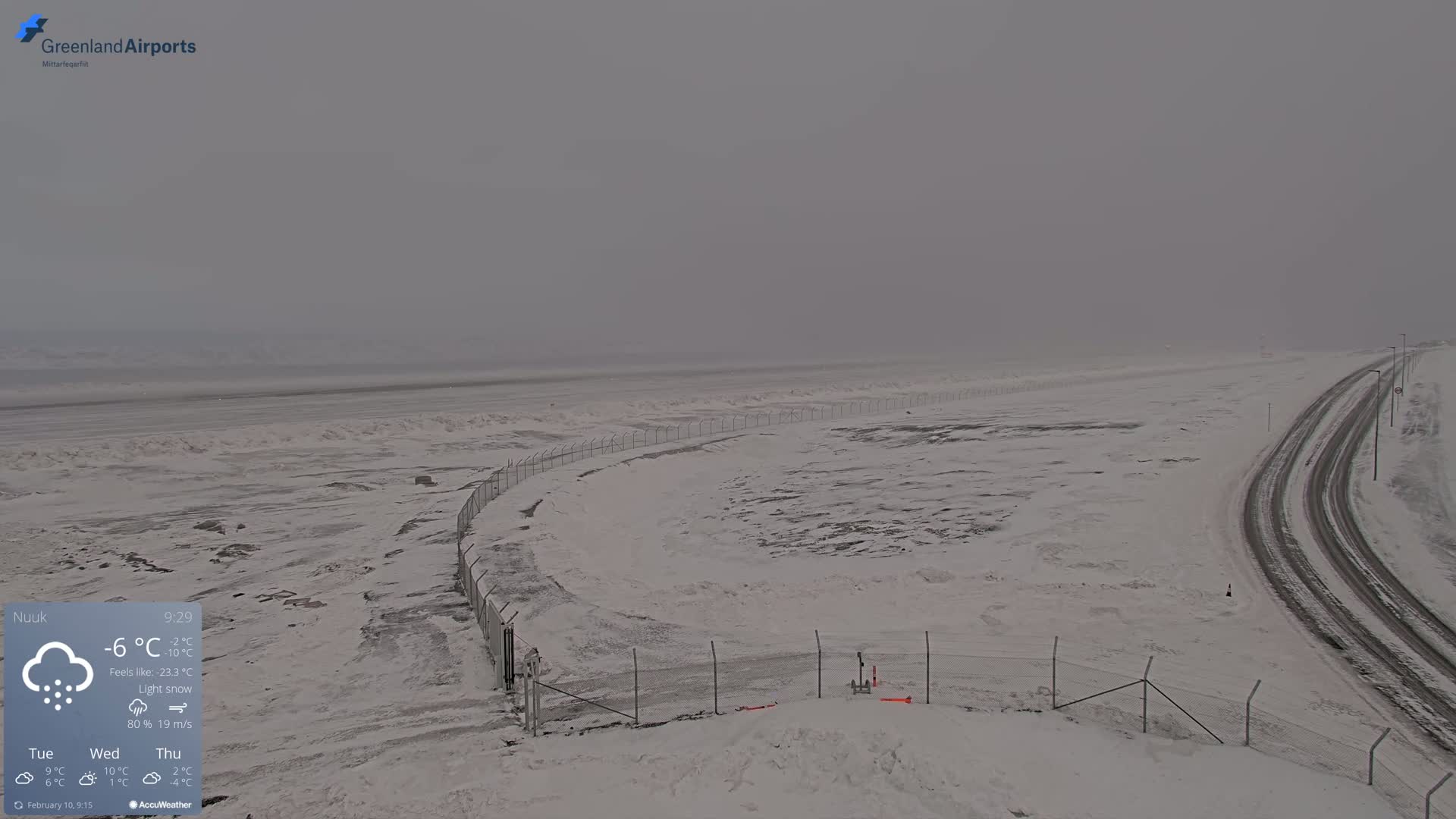 A snow-covered landscape with a road and fence is visible under a light snow and overcast sky.