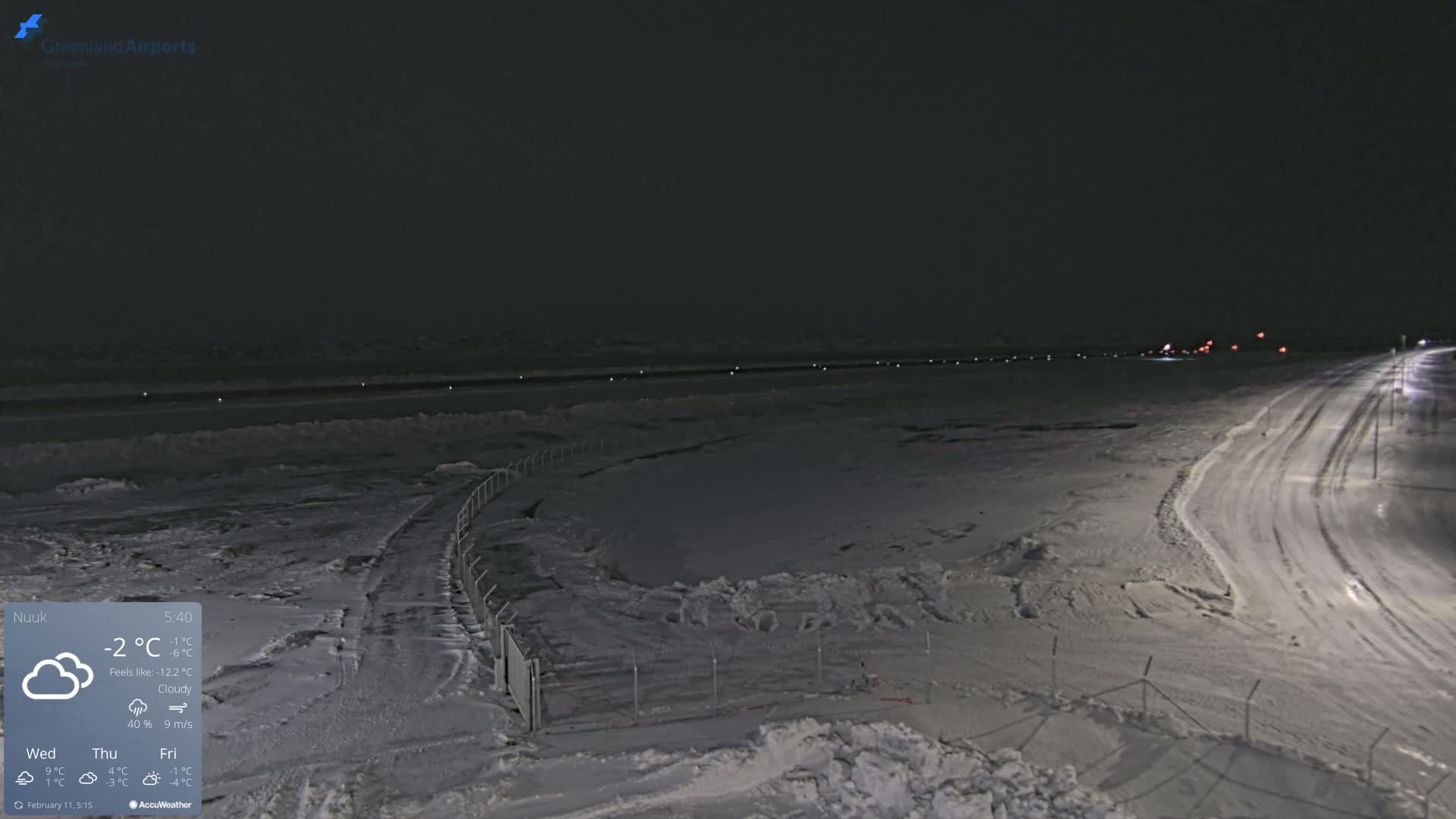 A snow-covered airfield at night under cloudy skies.