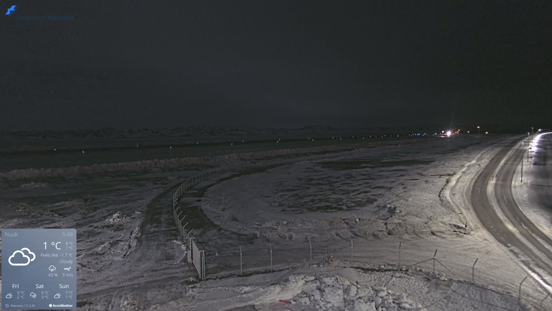 A snow-covered airfield at night under cloudy skies.