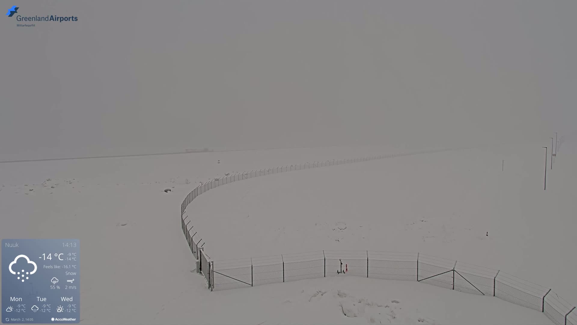 A snow-covered landscape with a chain-link fence is visible in heavy snow.