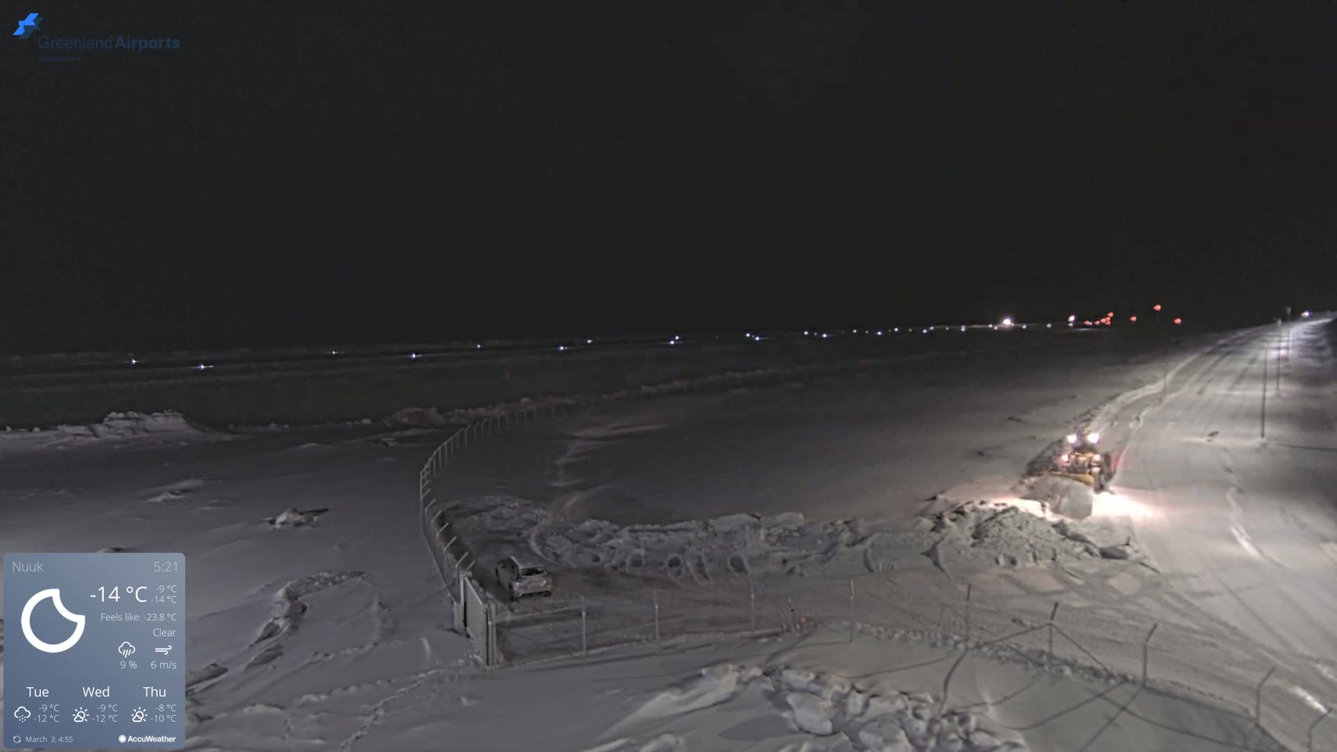 A snow plow clears a snow-covered road at night under a clear sky.