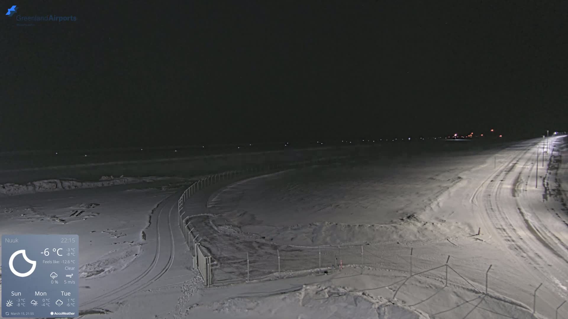 A snow-covered airfield is illuminated at night under a clear sky.