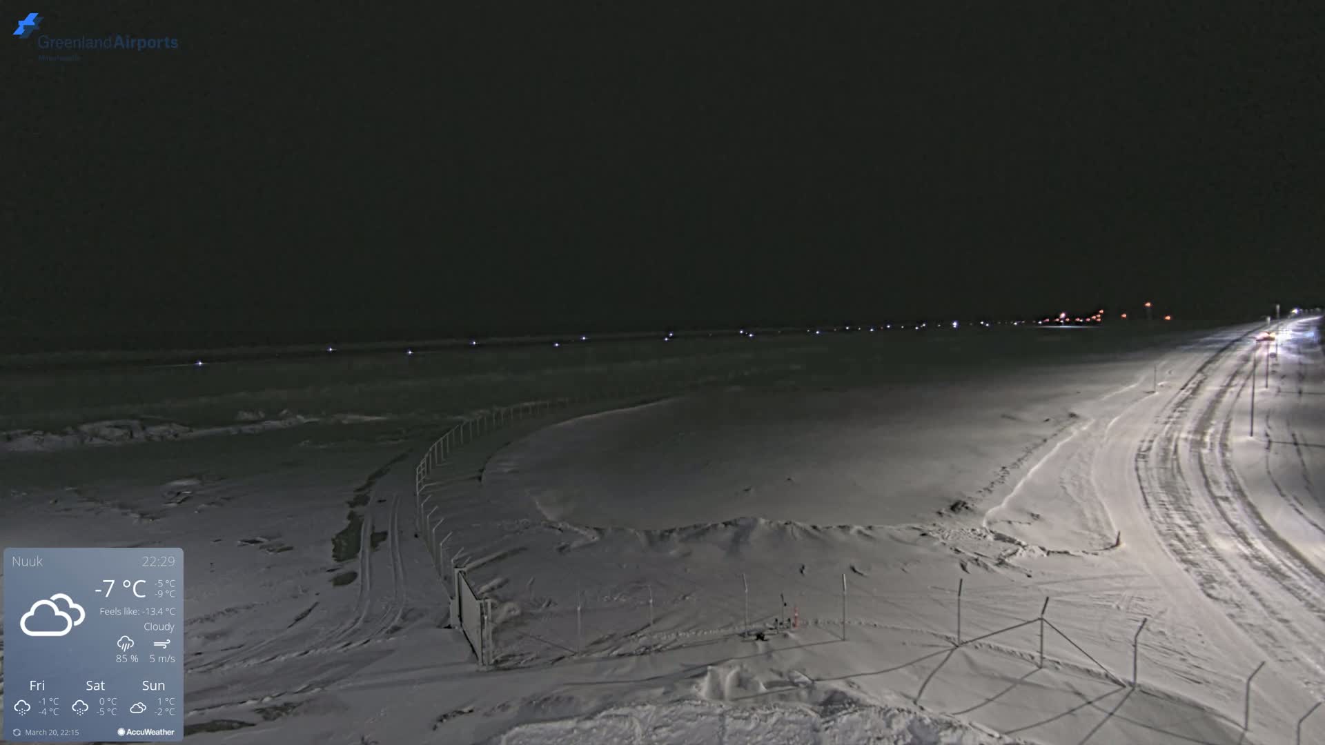 A snow-covered airfield at night under cloudy skies.