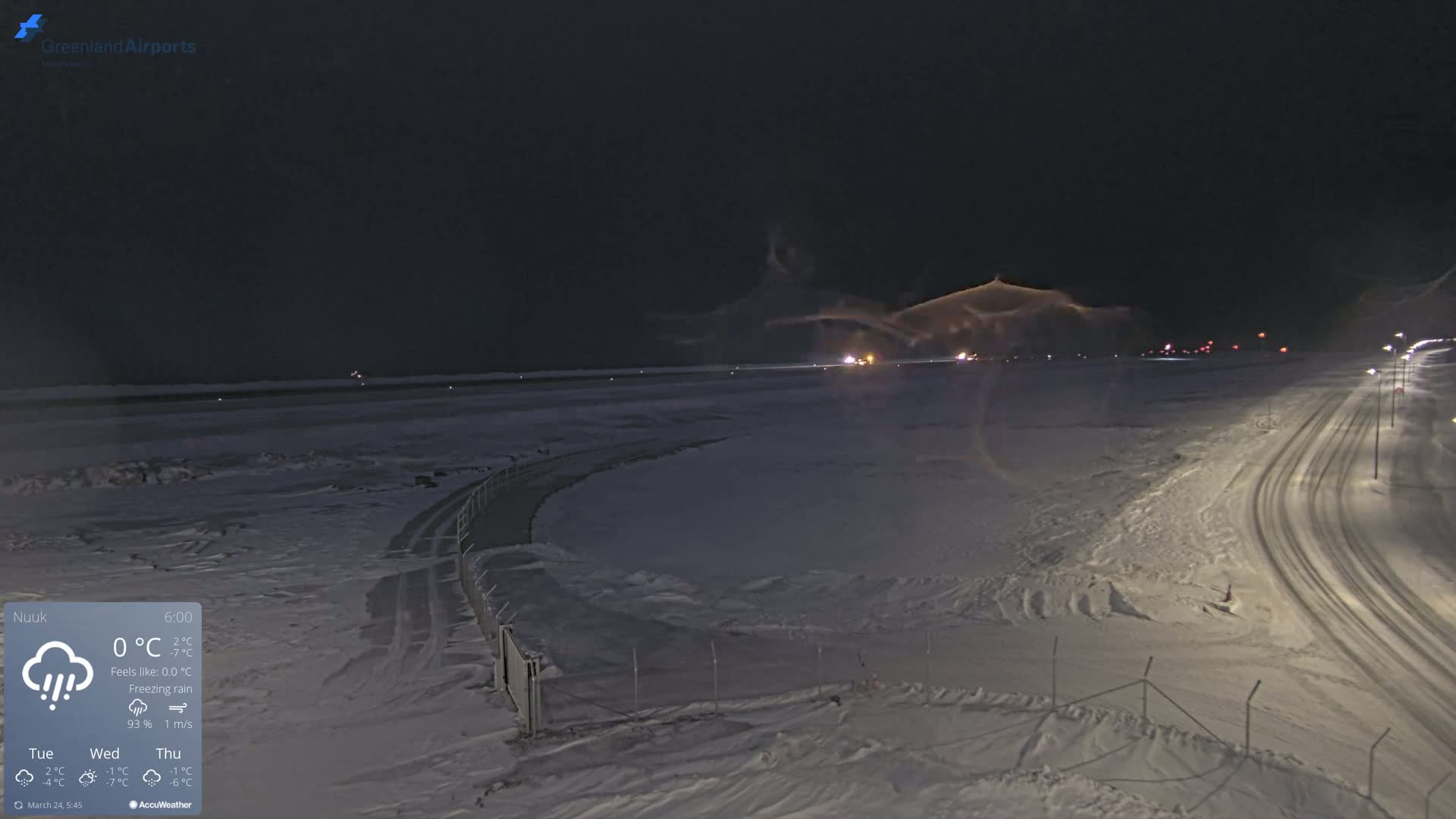 A snow-covered airfield at night under a dark, cloudy sky with freezing rain.