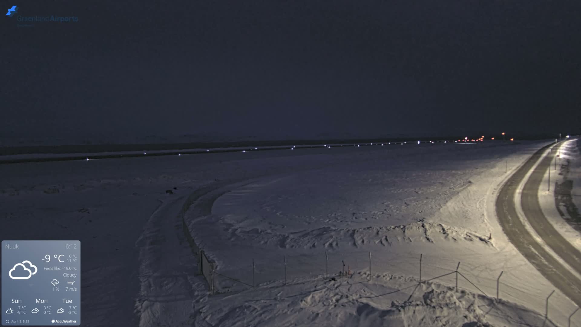 A snow-covered airfield at night under cloudy skies.