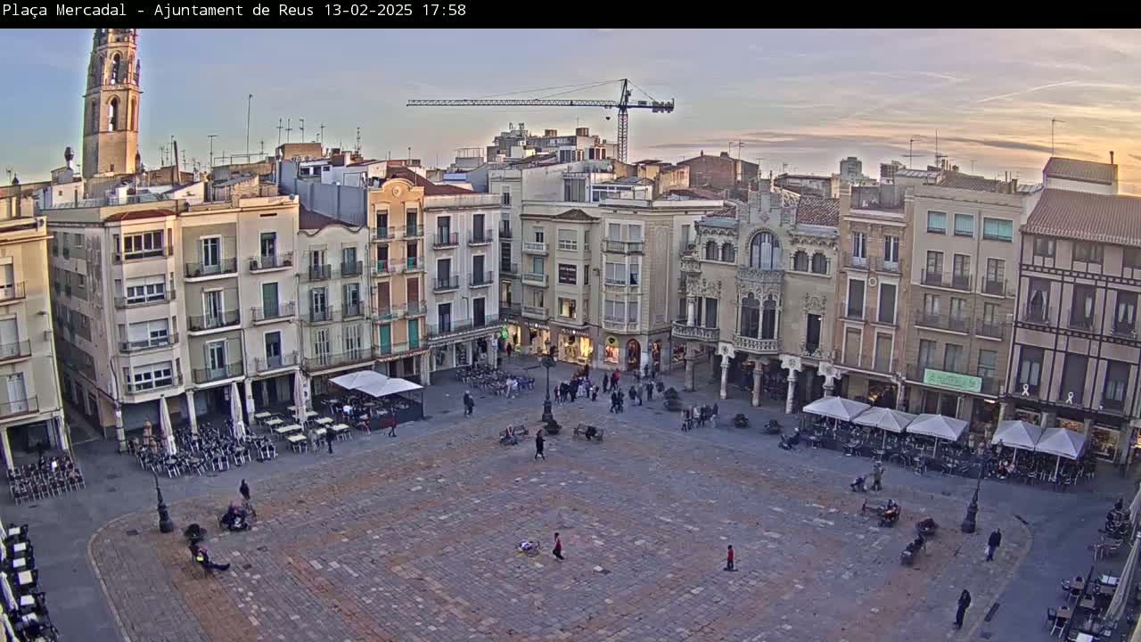 A large, mostly empty town square with surrounding buildings under a twilight sky.