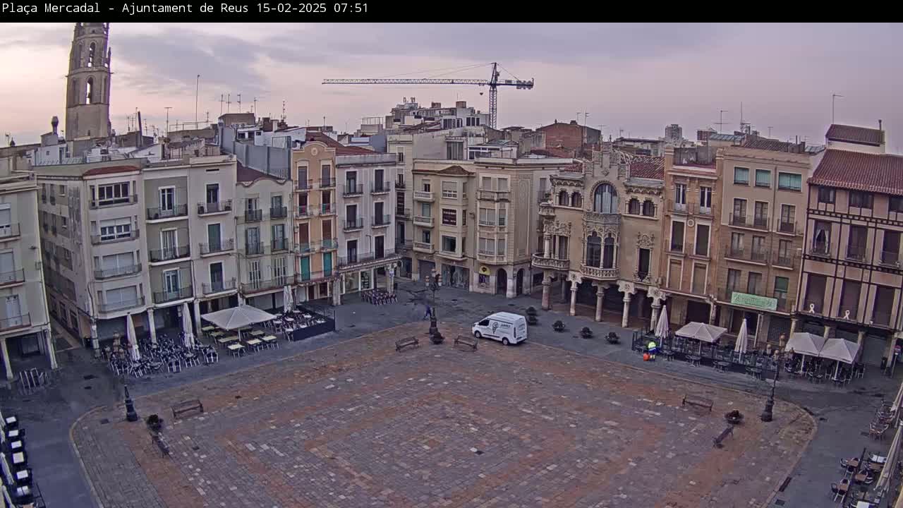 A mostly empty town square with several buildings surrounding it, under an overcast sky.