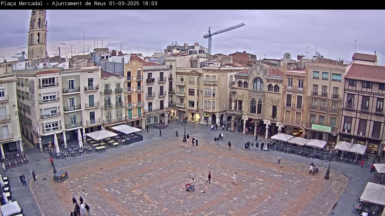 A large town square with several multi-story buildings surrounding it, under an overcast sky.