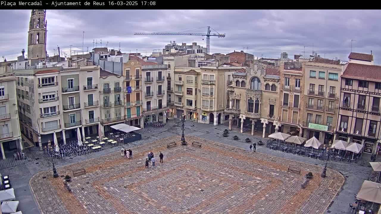 A large, cobblestone plaza is surrounded by multi-story buildings under an overcast sky.
