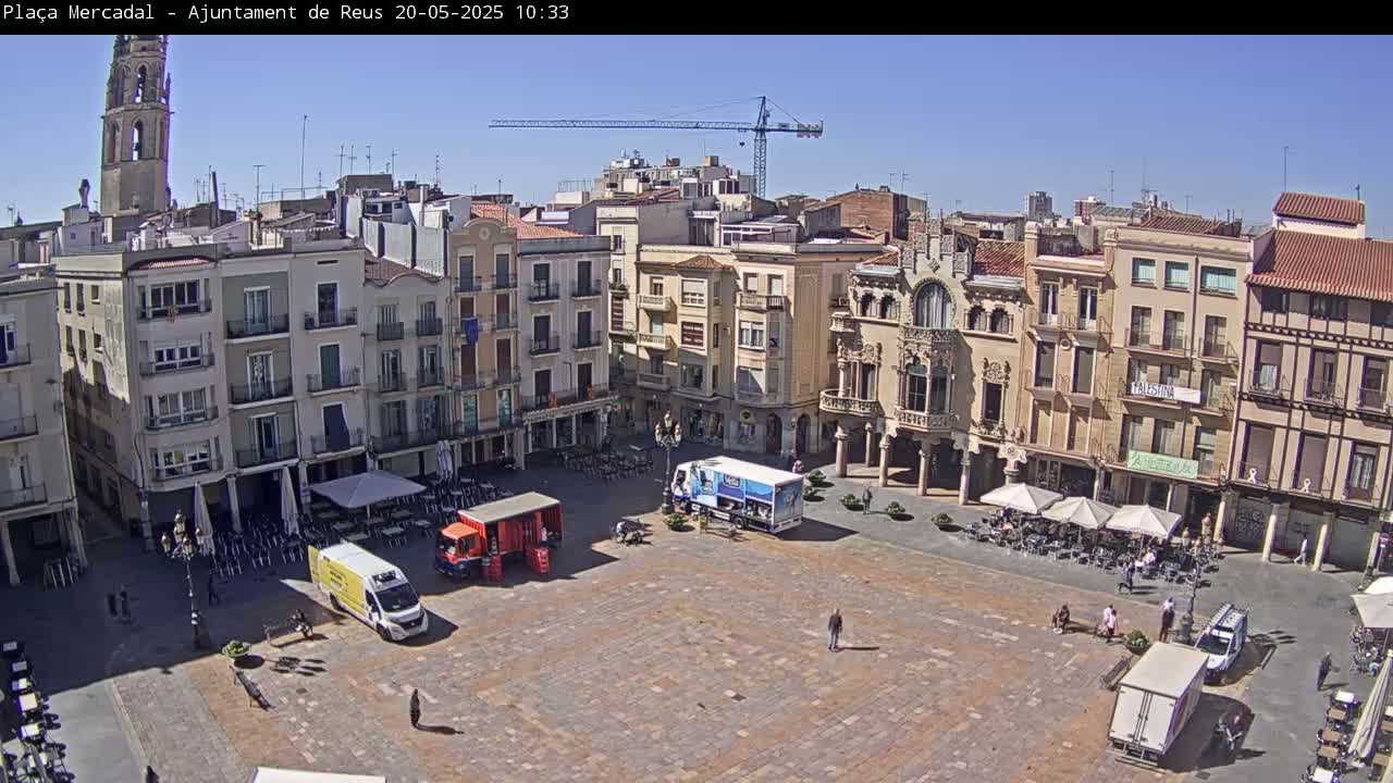 A large town square with several buildings surrounding it, under a clear sunny sky.
