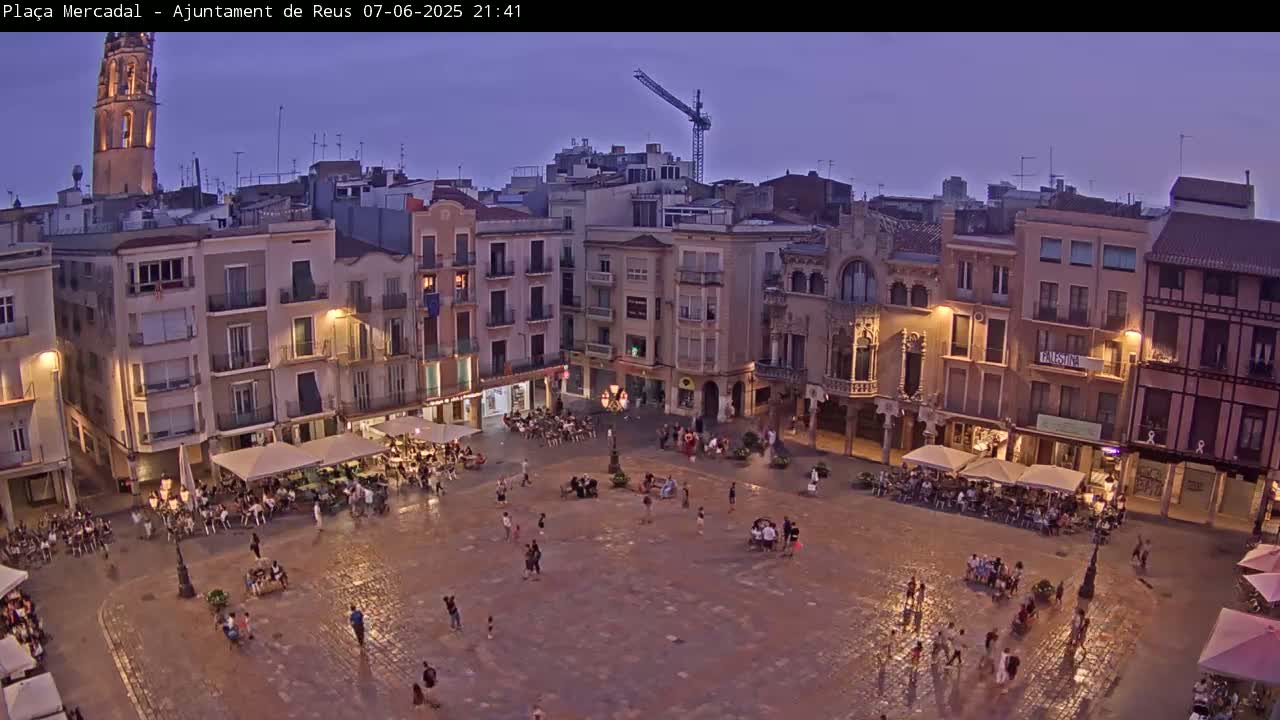 A town square at dusk, filled with people sitting at outdoor cafes and strolling around, under a twilight sky.