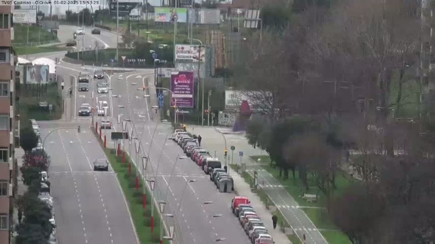 A mostly cloudy day reveals a multi-lane road with cars driving in both directions, alongside a bike path lined with bare trees and parked cars.