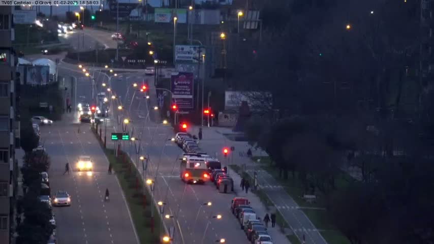 A high-angle, twilight view shows a multi-lane road with cars and a bus moving through an intersection, surrounded by trees and buildings.
