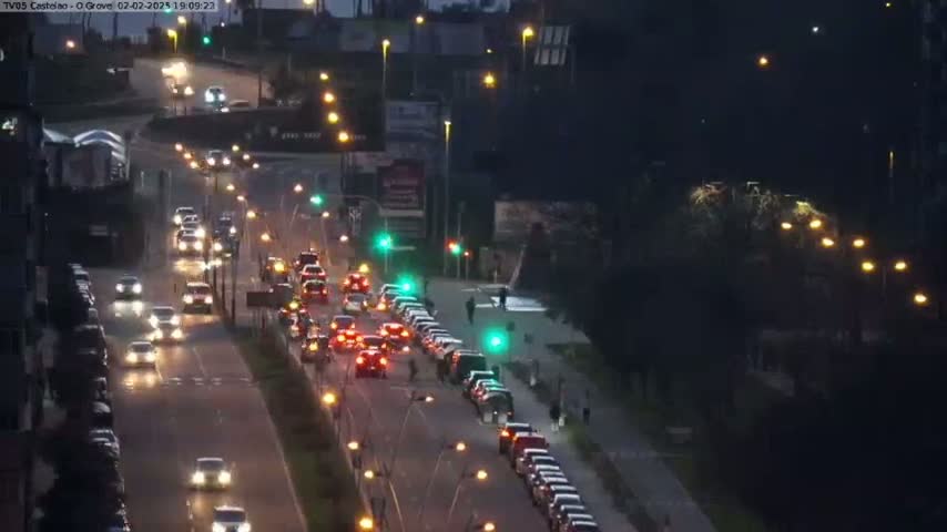 A nighttime view of a multi-lane road with moderate traffic flow under streetlights.