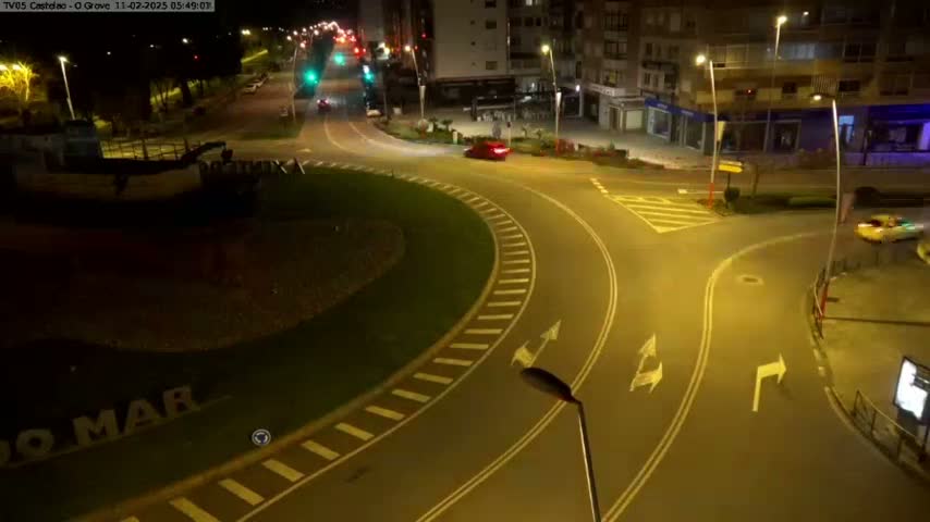 At night, a roundabout and adjacent streets are illuminated, with a few cars visible.