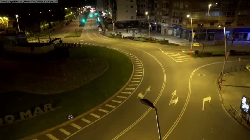 An empty roundabout and adjacent roads are illuminated at night by streetlights.