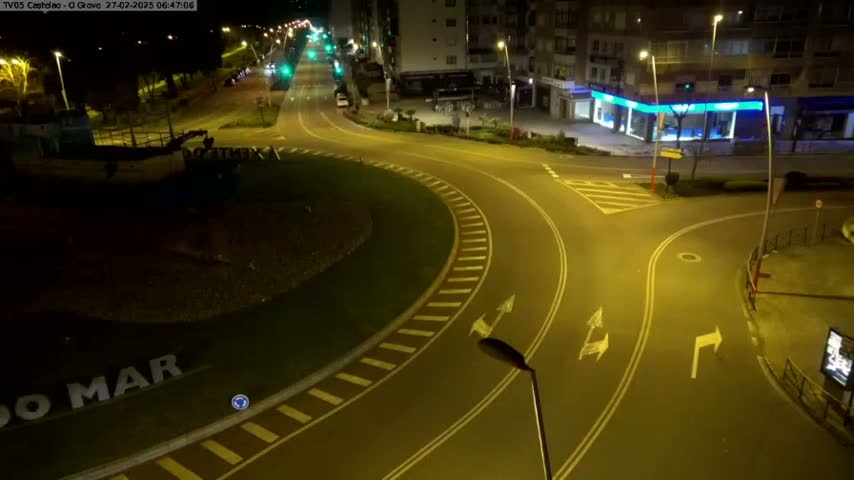 A mostly empty roundabout and intersecting roads are illuminated at night, with a partially visible boat in the lower left corner.