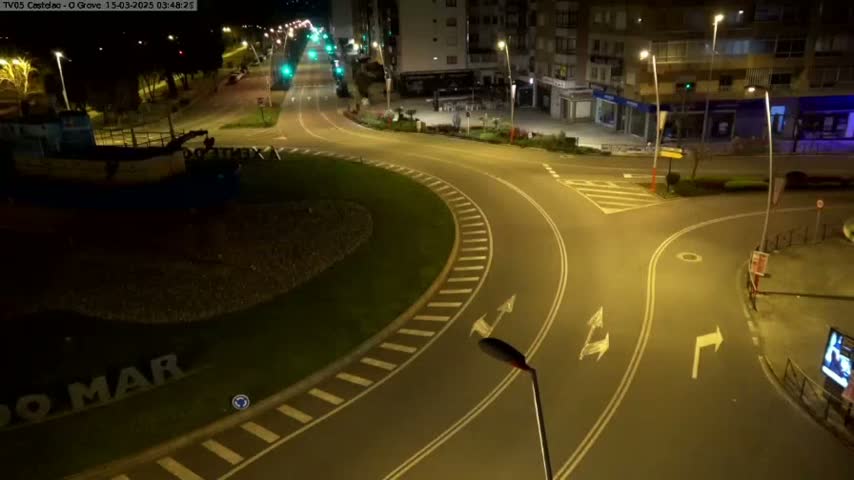 An empty roundabout and nearby streets are illuminated at night by streetlights.