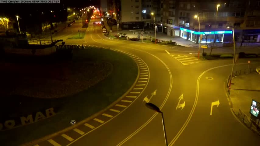 A nighttime aerial view of a roundabout and intersecting roads, illuminated by streetlights.