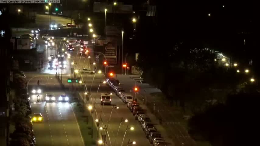 At night, a multi-lane road with cars driving in both directions is illuminated by streetlights.