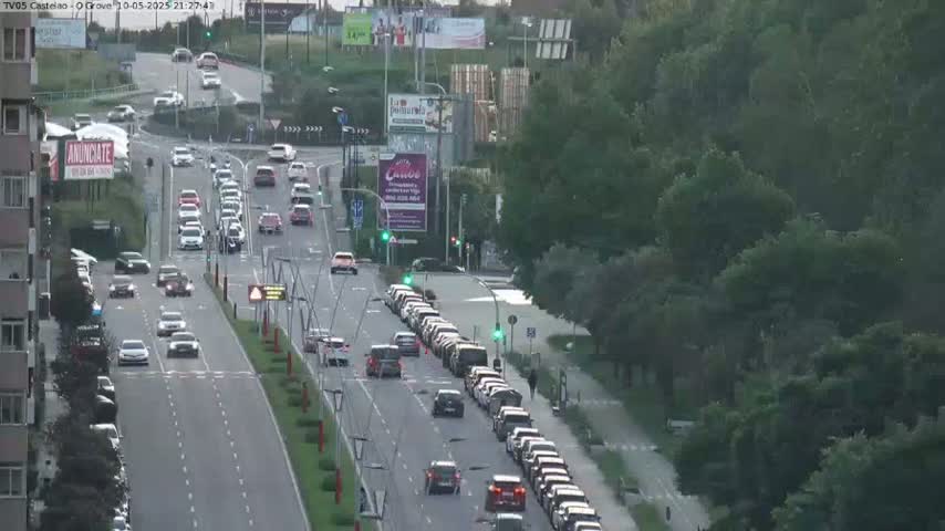 A multi-lane road with moderate traffic flows through a tree-lined area under a partly cloudy sky.