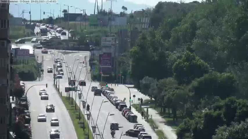 A highway with moderate traffic flows through a lush green area on a sunny day.