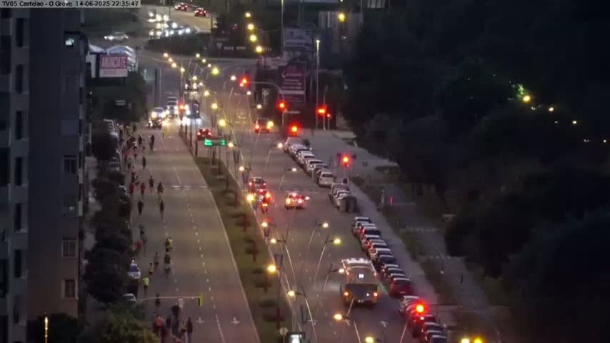 A multi-lane road with moderate traffic flows through a tree-lined area on an overcast day.