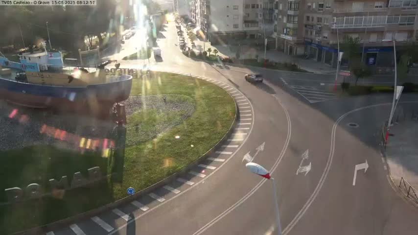 A sunny day reveals a roundabout with a large model of a fishing boat in the center, surrounded by roads and buildings.