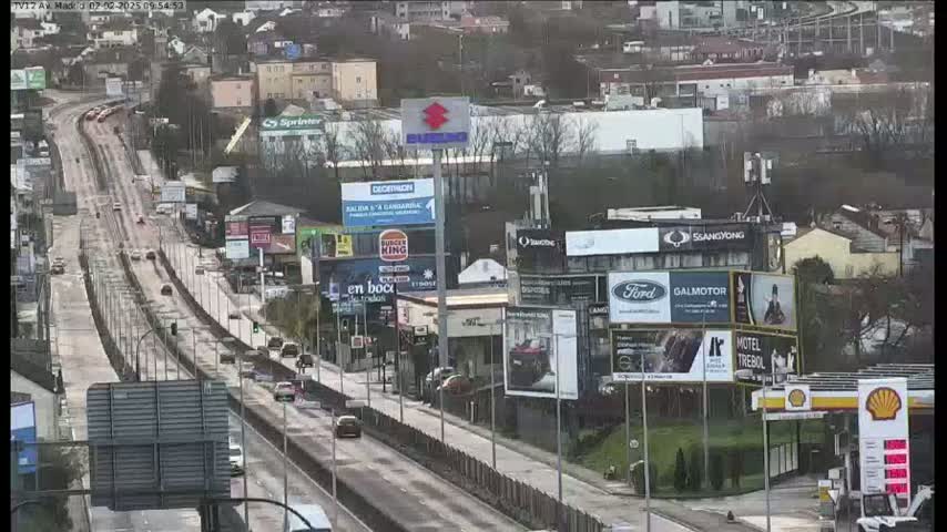 A slightly overcast day shows a highway with moderate traffic passing by numerous billboards and buildings.