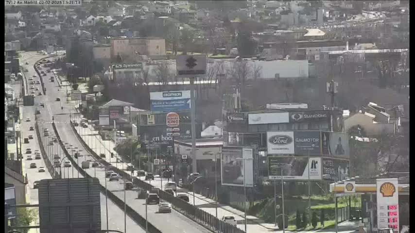 A highway with moderate traffic flows through a city on a partly cloudy day.