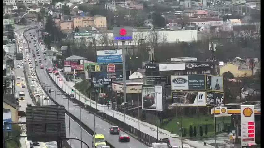 A highway with heavy traffic is seen on an overcast day, lined with billboards and buildings.