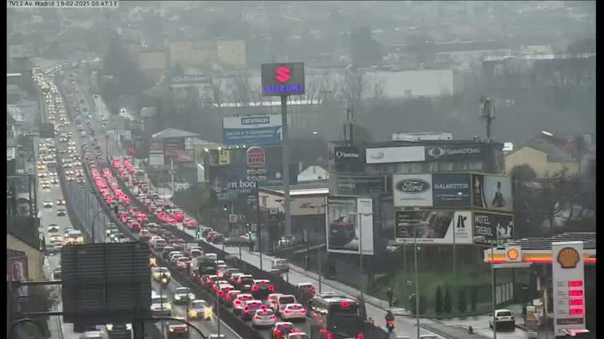 A long line of slow-moving traffic stretches along a highway under an overcast sky.